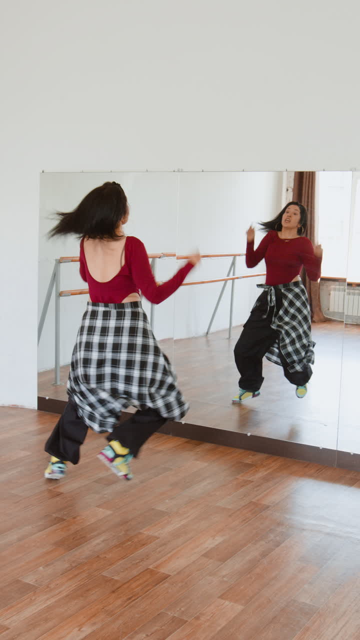 Woman practicing dance movements in a studio with a mirror