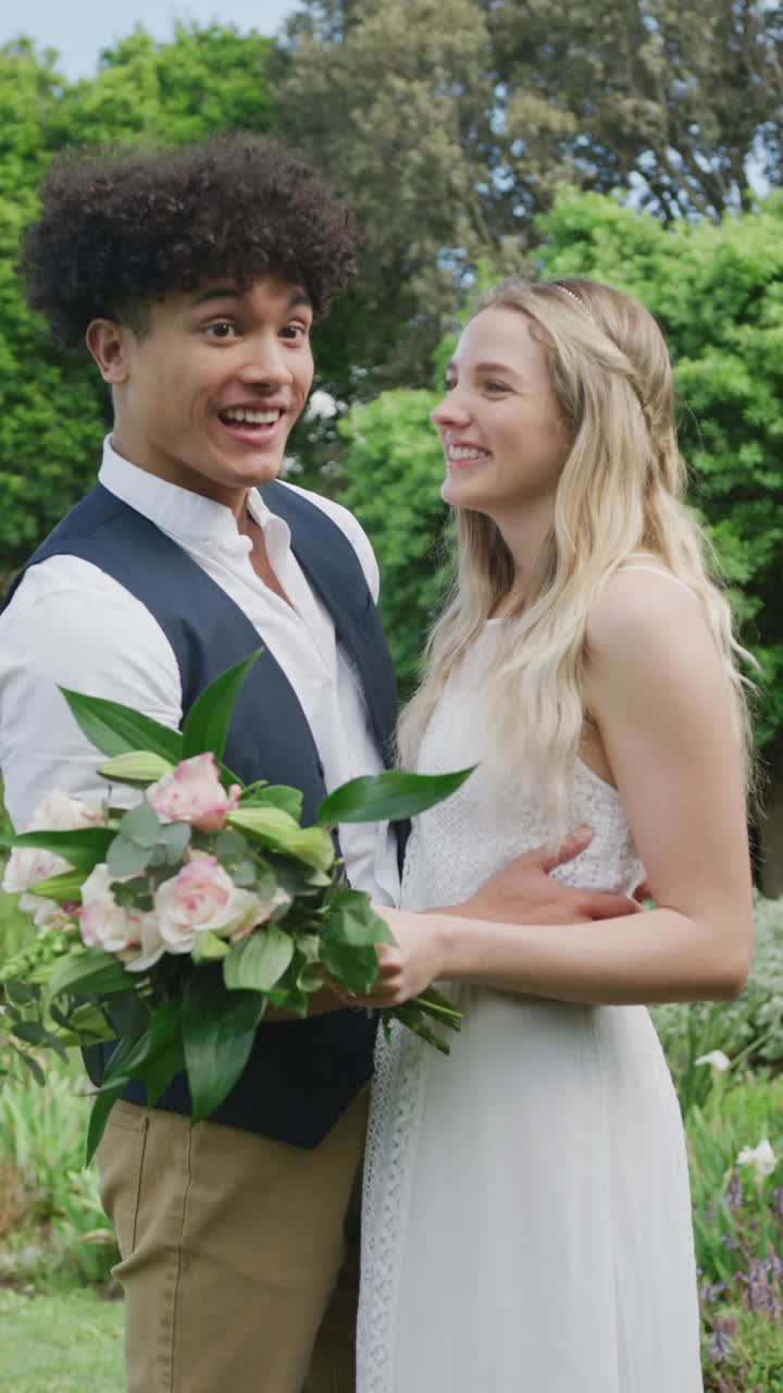 Video verticale di ritratto di coppia felice multietnica in giardino in una giornata di sole a un matrimonio