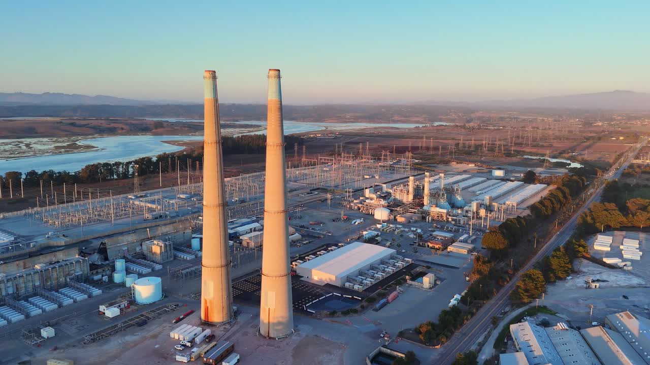 Moss Landing battery energy storage site (BESS) with twin stacks at golden hour light
