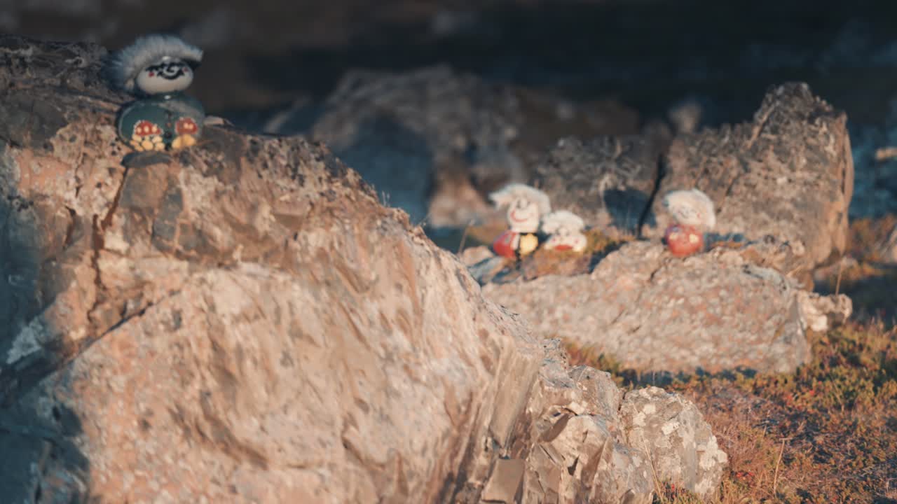 lindas figuritas de troll de piedra hechas a mano iluminadas por el sol, sentadas en rocas grises y escarpadas cerca de la carretera