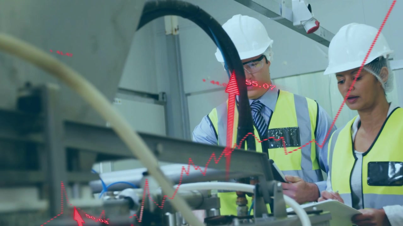 Man tapping tablet and woman writing clipboard inspecting factory machine while causing red graphs