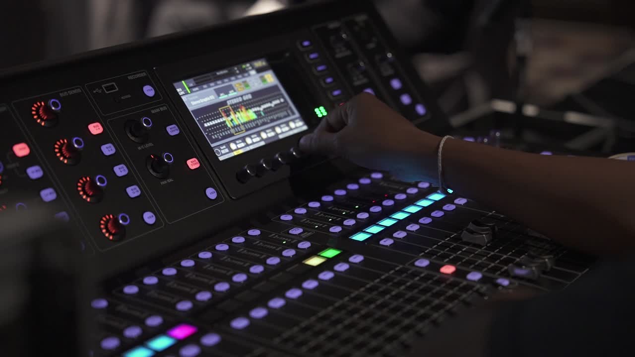 Close up of a sound guy mixing audio levels at a live event indoors on the board
