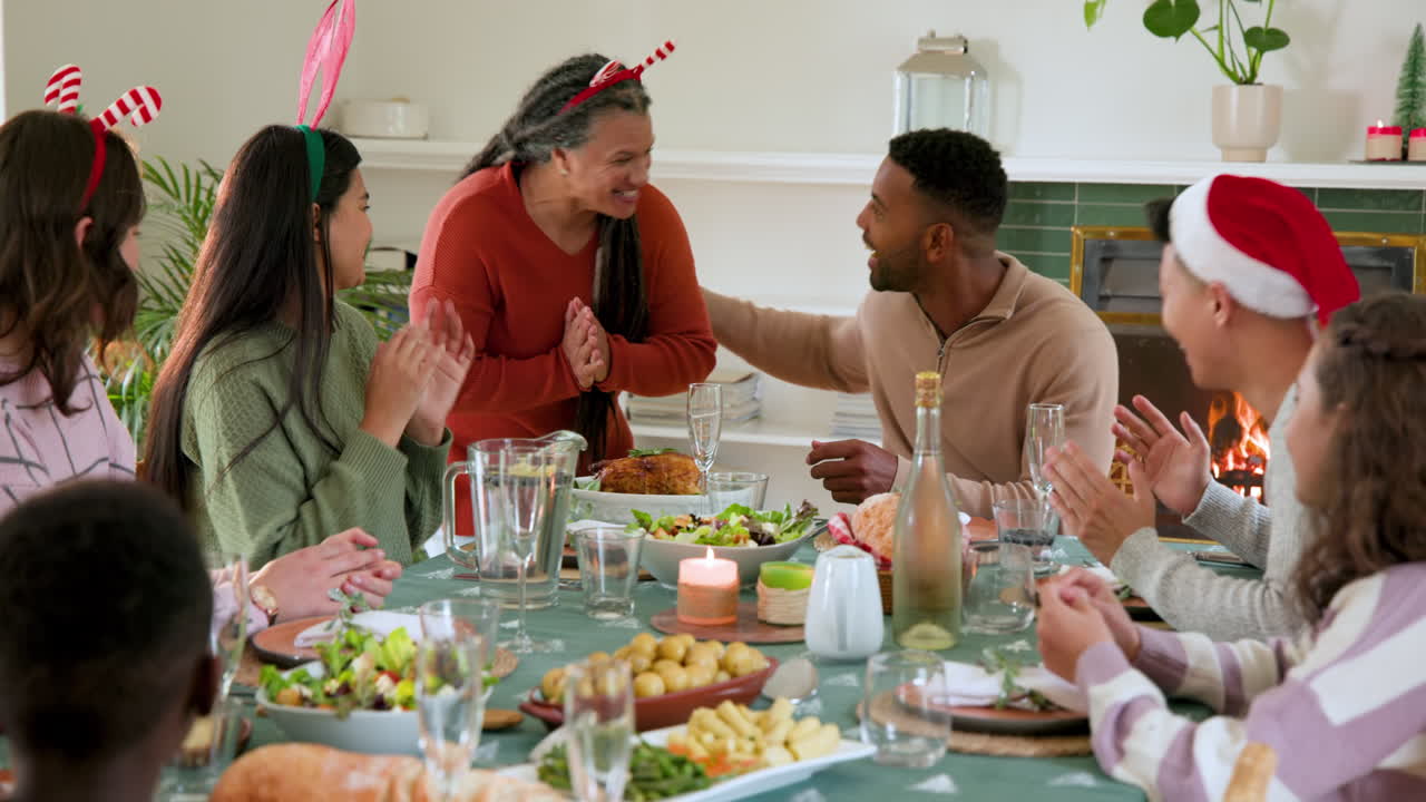 Famille diversifiée célébrant le dîner de Noël ensemble, partageant joie et rires près de la cheminée.