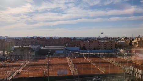 Vista-Aérea-Del-Horizonte-De-La-Ciudad-De-Madrid-Durante-La-Mañana-Temprano-Con-El-Cielo-Azul-Y-La-Cancha-De-Tenis-Como-Primer-Plano