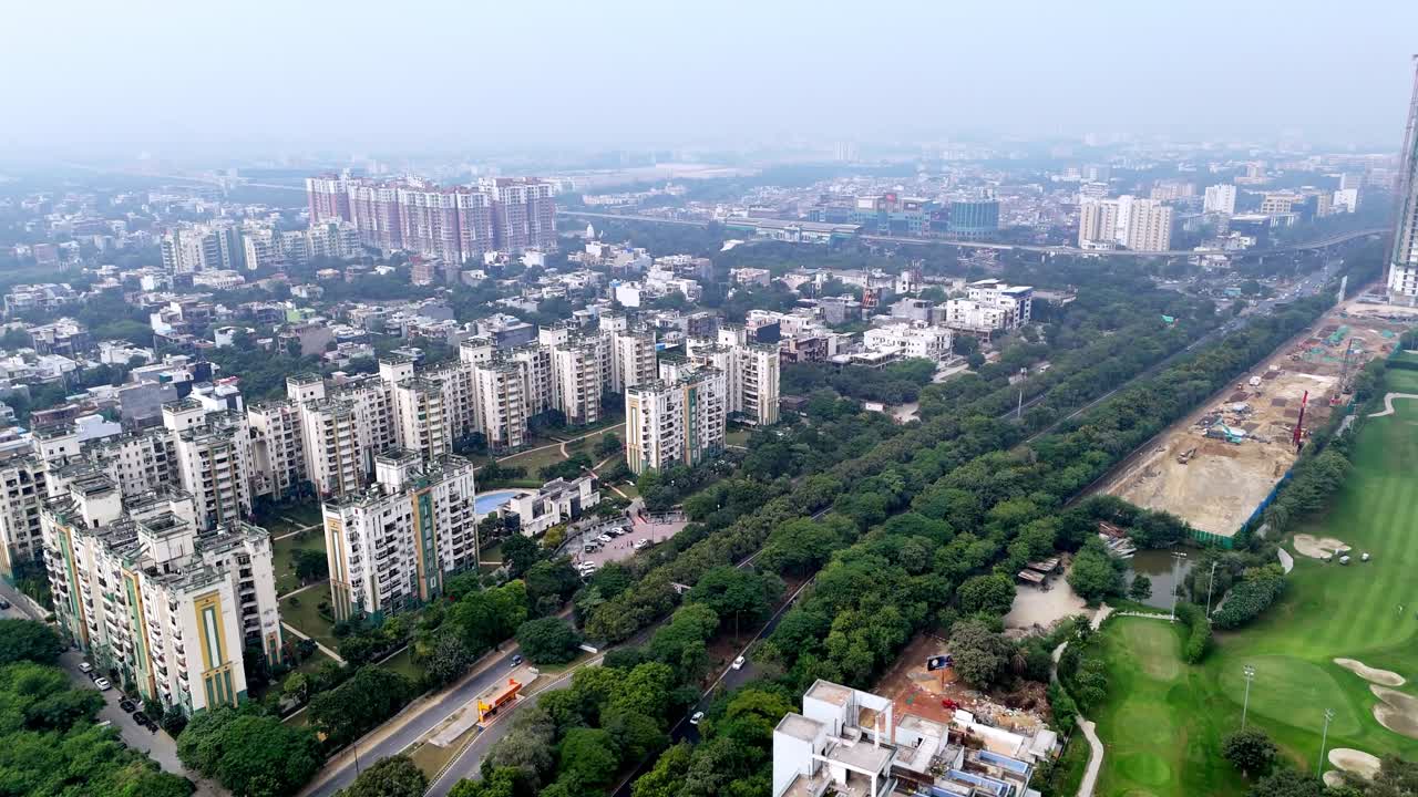 Vista aerea di grattacieli in costruzione a Greater Noida, con gru che trafiggono uno skyline avvolto dallo smog, riflettendo una rapida crescita urbana in mezzo a un evidente inquinamento atmosferico