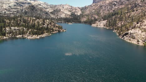 expansive aerial view of a high sierra lake with snowy granite peaks in the distance