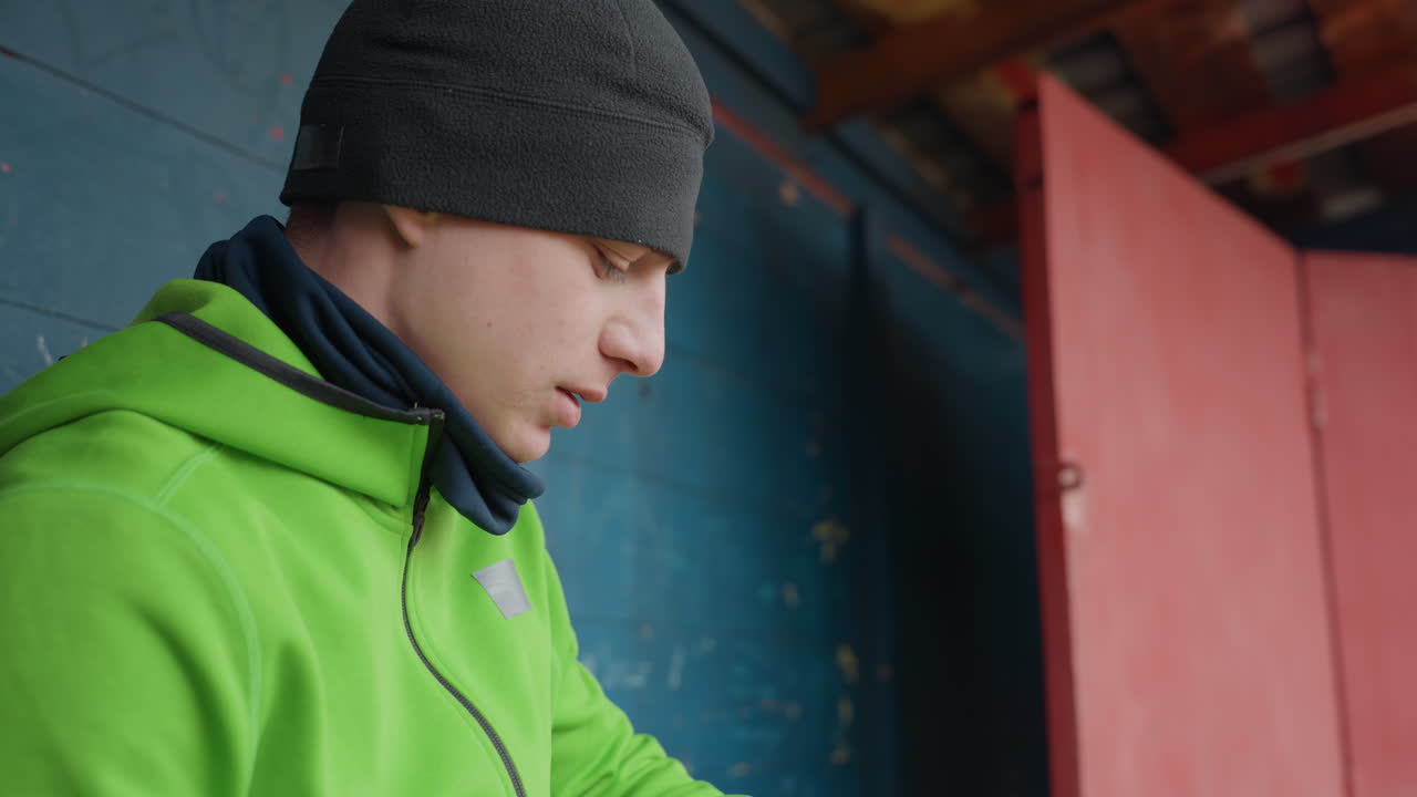 Un hombre vestido de verde se rehidrata durante una pausa; un atleta caucásico se detiene para hidratarse con una técnica de respiración tranquila; un deportista vestido con una chaqueta verde bebe agua con cuidado mientras se toma un momento para hidratarse.