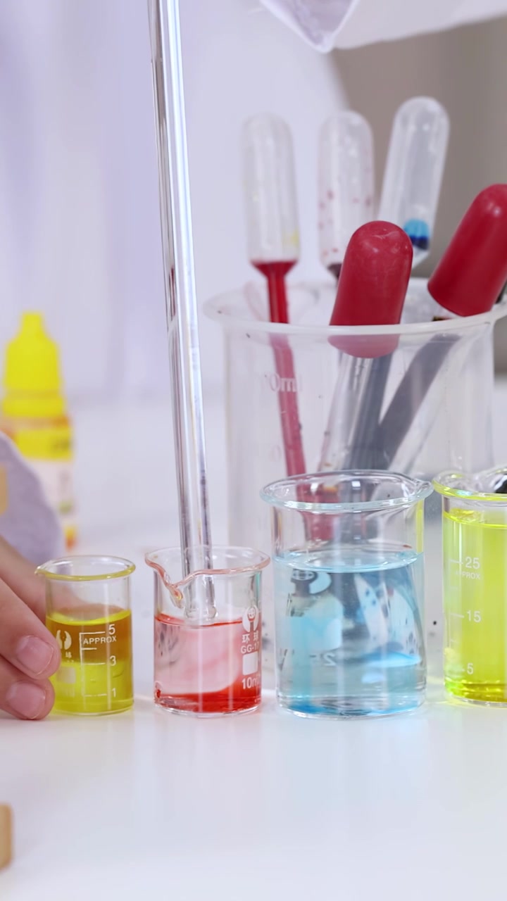 Primo piano di un ricercatore che trasferisce sostanze chimiche colorate usando una pipetta di vetro in un laboratorio luminoso