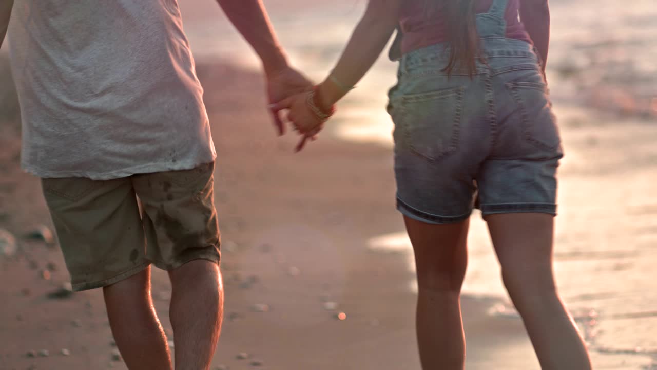 Close-up of young couple holding hands at the beach