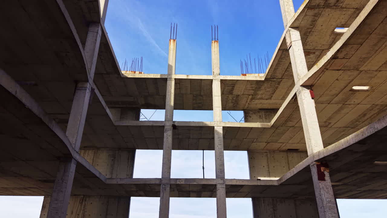 Exploring the skeletal structure of an abandoned building under a clear blue sky reveals the beauty of urban decay and nature's resilience