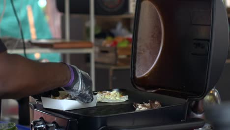 Tortilla-wrap-with-nutritious-fillings-placed-into-paper-container-over-grill,-filmed-as-medium-shot-in-slow-motion-style