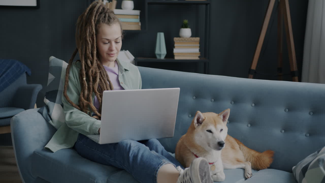 Woman Working on Laptop with Dog on Couch