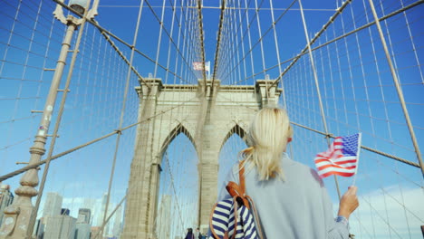 a woman with the flag of america in her hand is on the brooklyn bridge