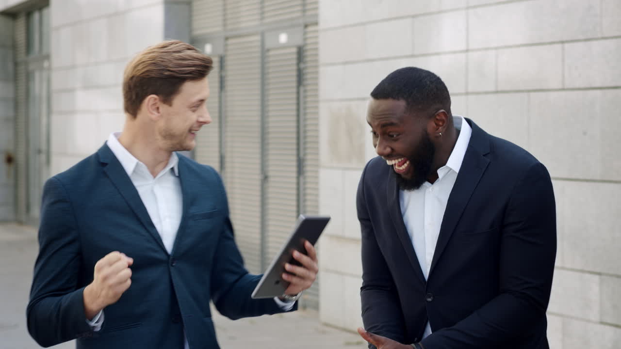 Businessmen reading good news on tablet. Professionals celebrating victory