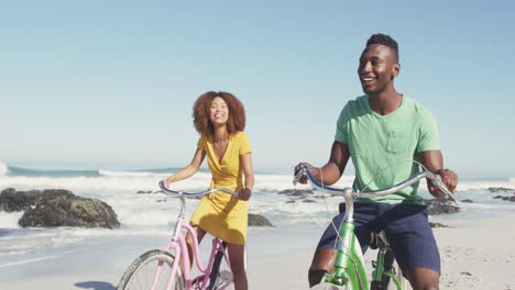pareja afroamericana montando una bicicleta en la orilla del mar