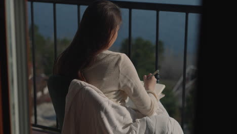 woman writing on balcony with view