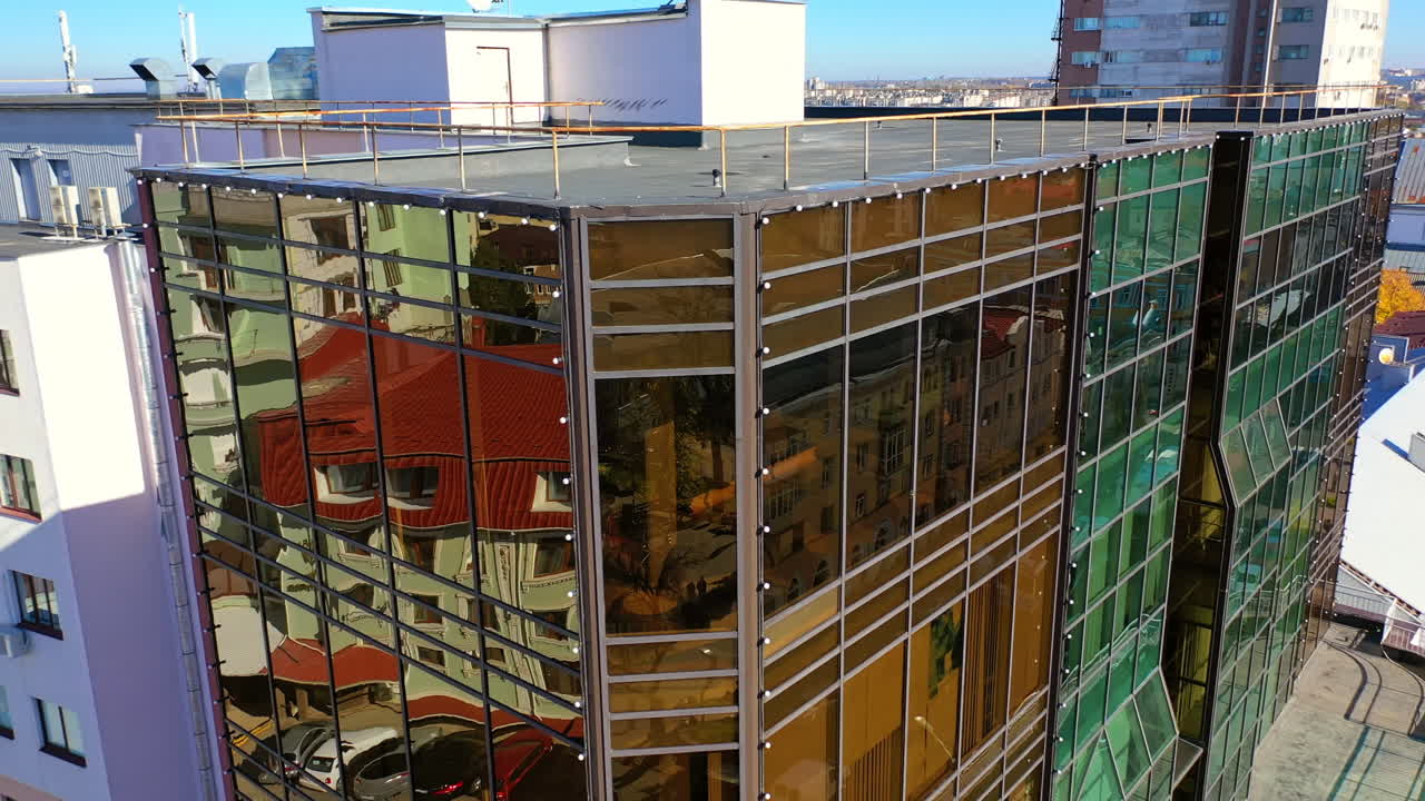 Flying around the top of the building with mirror windows. Sight of the road in the city centre. Top view.