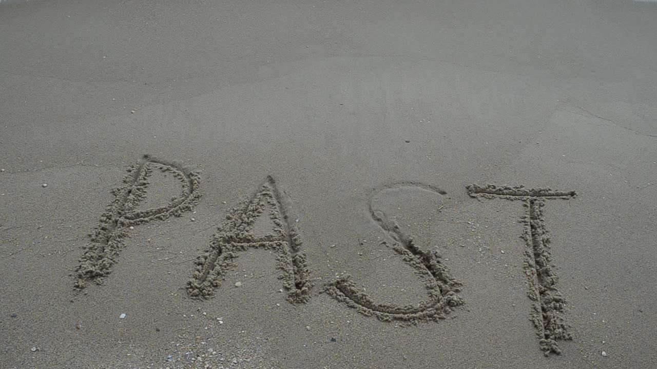 The inscription "PAST" on a wet sand seacoast. Shooting on the beach