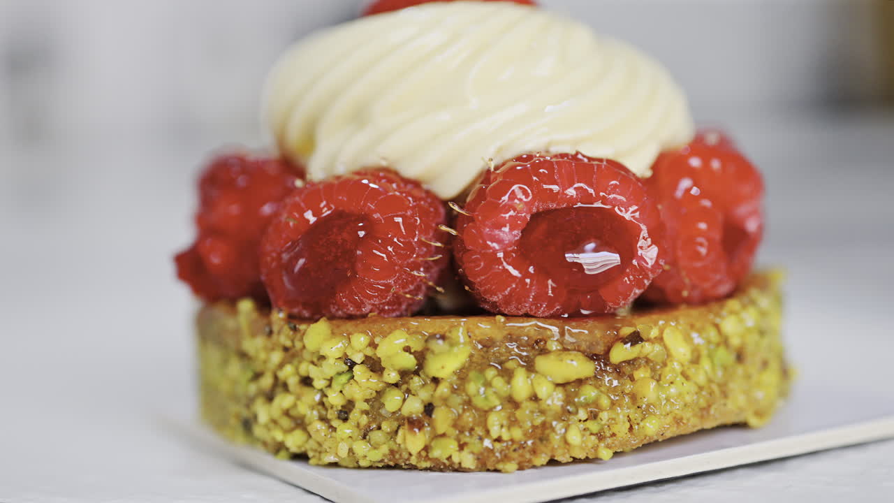 Close up of a pistachio raspberry tartlet on a white plate