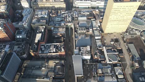 aerial drone flight over market street in manchester city centre showing the rooftops and empty streets during lockdown on a hazy sunny morning