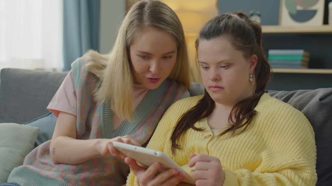 Woman Teaching Girl with Down Syndrome How to Use Tablet
