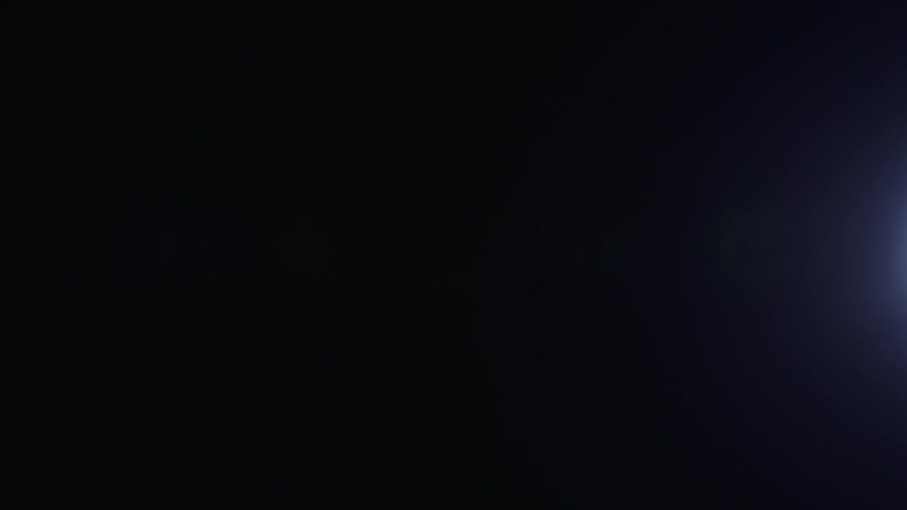 Abstract shot of a light ray flare moving across a black background, creating a clean glowing visual effect