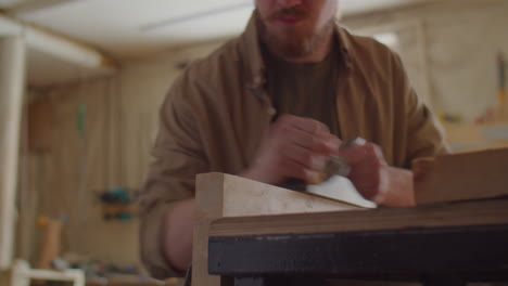 carpenter shaping wooden plank with hand plane