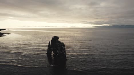 drone flying slowly in circulair motion around hvítserkur rock in the early morning in iceland in 4k