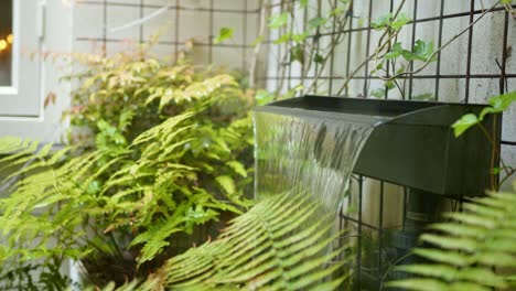 decorative artificial waterfall in a public garden with ferns - close up