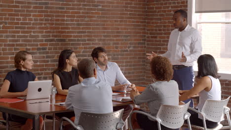 businessman standing to address boardroom meeting