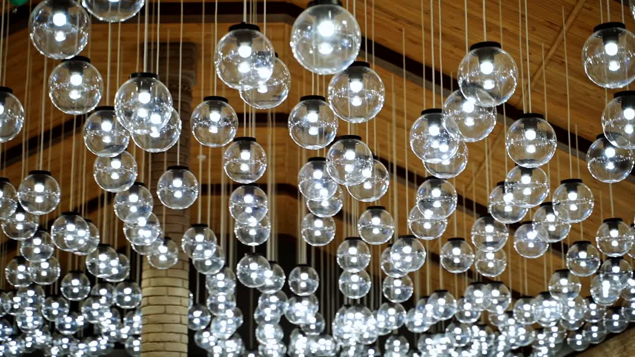 Round transparent bulbs hanging from wooden celling. View from below. Modern interior. Modern light classic lamp hanging from celling. Vintage lamps, bulb lamps. Video from below.