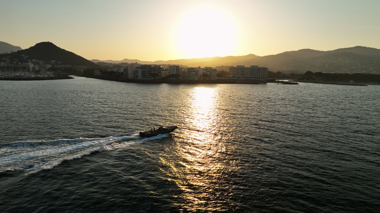 Silhouette di una barca al tramonto con Mandelieu la Napoule sullo sfondo, vista aerea