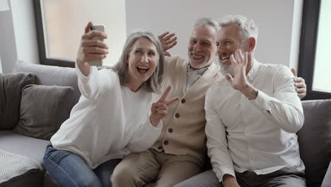 Grupo-De-Felices-Amigos-Mayores-Sentados-En-El-Sofá-Y-Tomando-Un-Video-Selfie