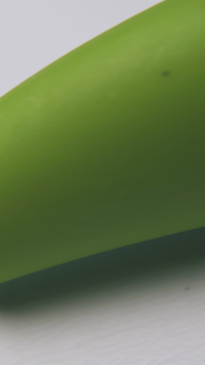 stainless vegetable peeler with bright green plastic handle lies on clean white background extreme close view