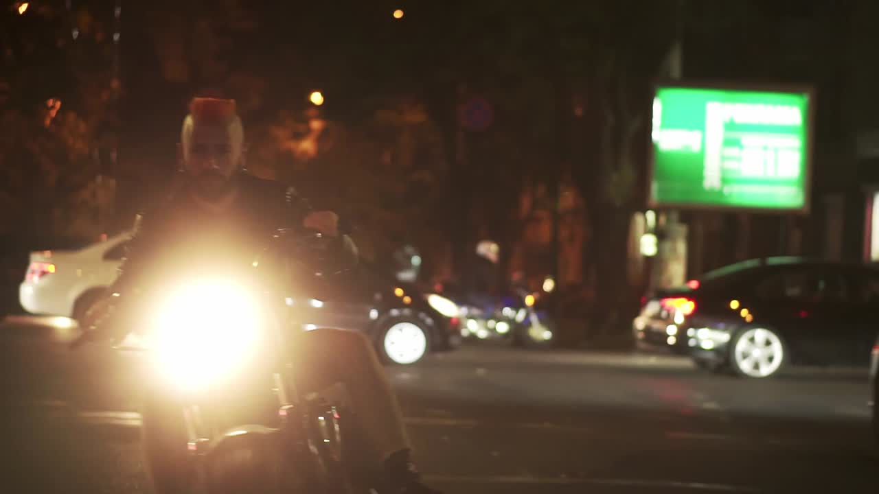 세련된, 잔인한 오토바이 운전자는 거리 도로에서 밝은 헤드라이트로 도시에서 자전거를 운전합니다.