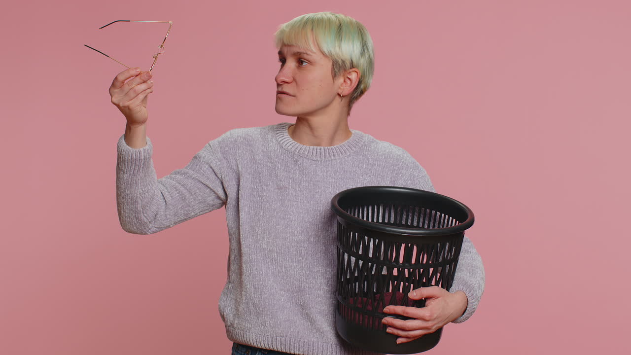 Young woman with green hair holding glasses and a trash can