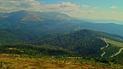 aerial drone shot view of a mountain road with tarcului mountains in the background