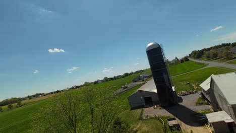 vuelo de drones fpv sobre una granja con un coche en la carretera durante un día soleado en el campo americano