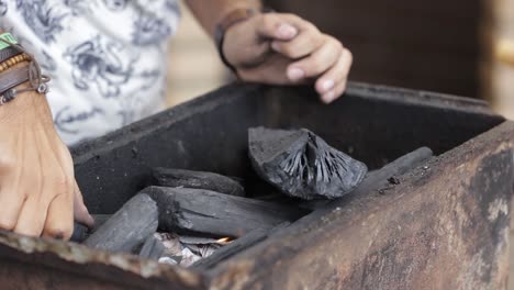 Starting-a-fire-on-coal-with-lighter-in-an-improvised-barbecue-pit