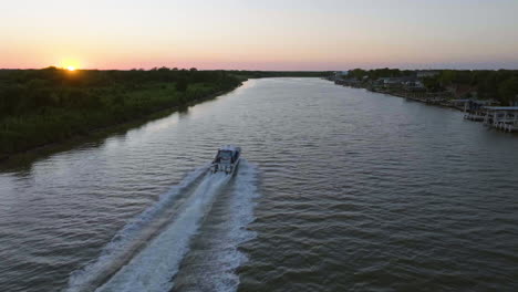 vista aérea siguiendo una lancha a motor conduciendo en un canal al atardecer en texas, ee.uu.