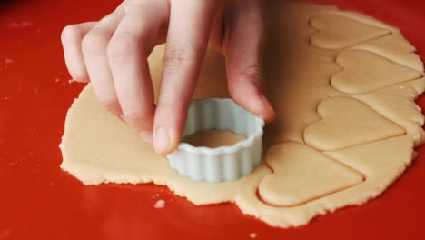 close up woman hand making cookies in the round shape on the red silicone baking mat.