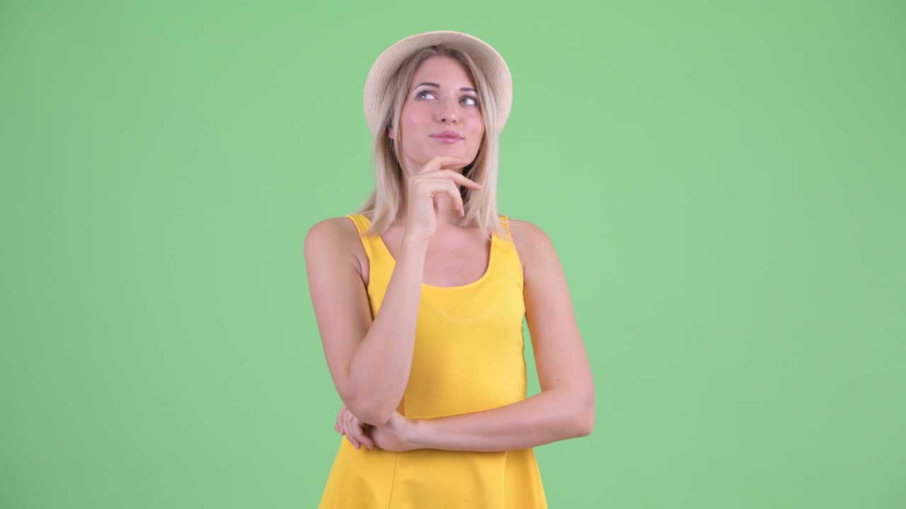 fotografía de estudio de una joven turista sonriendo y pensando contra un fondo verde