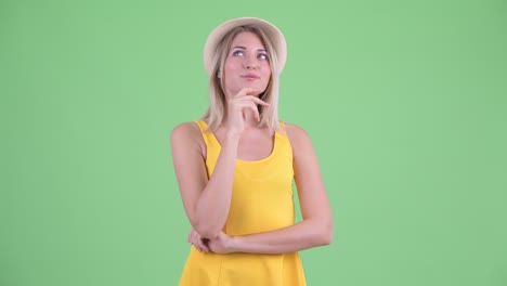 fotografía de estudio de una joven turista sonriendo y pensando contra un fondo verde