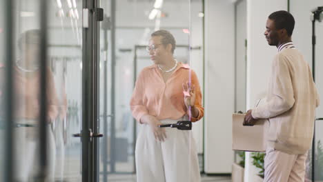 american businesswoman shows an office to a young man and opens the door for him, then the two of them enter