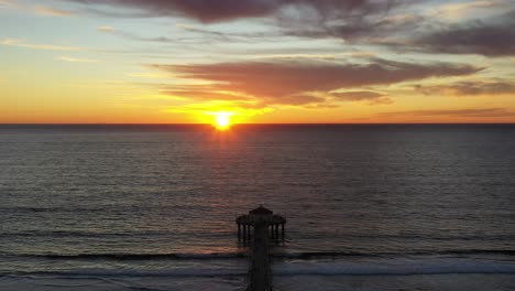 scenic sunset over manhattan beach pier in california - aerial drone shot