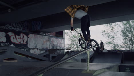 young hipster riding on bmx bike at urban skate park. biker training skills