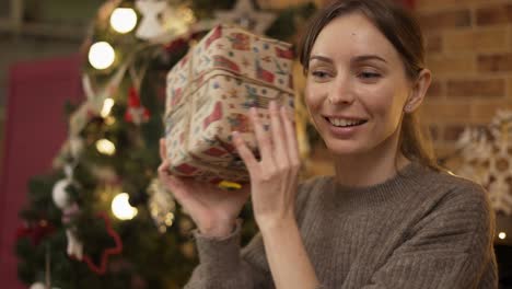 Blonde-Frau-Schüttelt-Weihnachtsgeschenkbox-Und-Rät,-Was-Drin-Ist,-Nahaufnahme