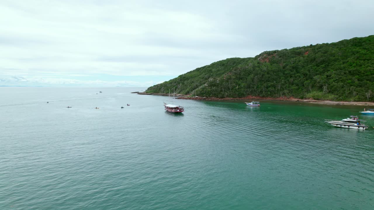 Dolly in establishing aerial view of a large red tourist boat on the shore of Tartaruga beach on a tour along the coast of B&uacute;zios, Brazil