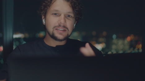 curly-haired white man talking by video call at night