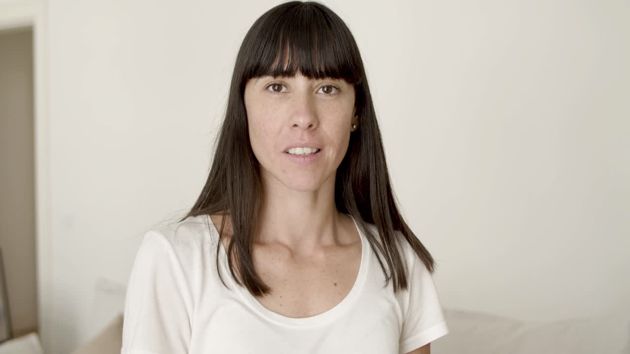 joven de cabello oscuro feliz posando en el interior del hogar